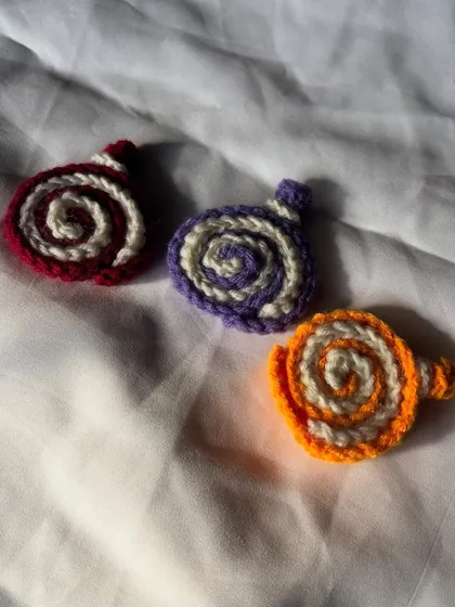 Here are three of my crochet cake roll charms together. I have them in red, purple, and orange, all with a cream swirl.