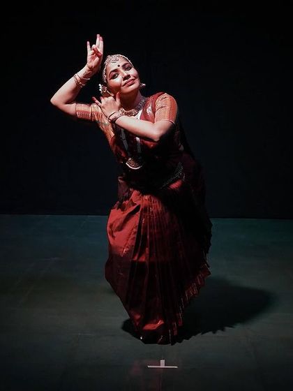 A full-length shot of the dancer from 'Rasayatra', demonstrating a classic Bharatanatyam pose. The image captures the elegance and strength of the art form.