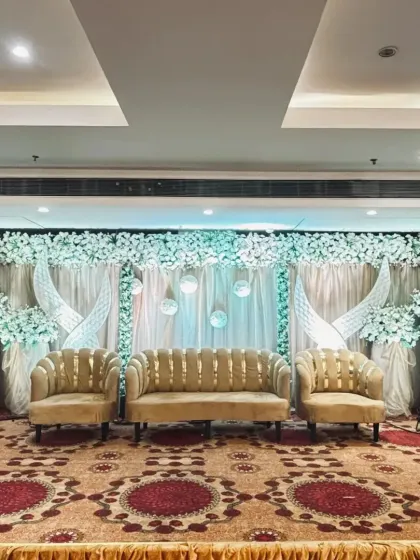 A beautiful stage decoration featuring white drapes, floral arrangements, and unique crescent-shaped props. This setup at a Vashi hall is perfect for a dreamy reception.