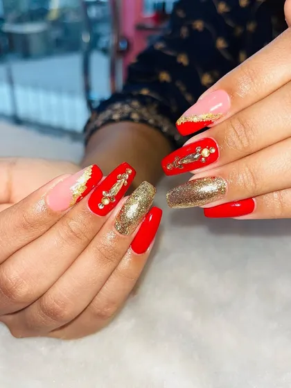 Making a statement with this bold and glamorous nail set. It combines vibrant red and shimmering gold glitter nails with intricate gold foil and gem accents, perfect for any bride or festive occasion.