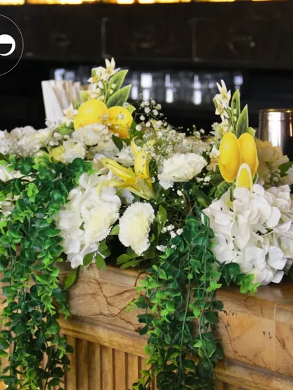 A lush floral runner with cascading greenery adorns the bar at a citrus-themed event, transforming a functional space into a beautiful decor element.