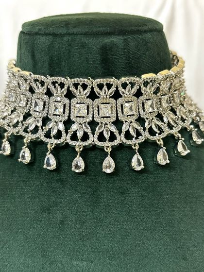 This wide American diamond choker features a geometric pattern and teardrop dangles. It's a bold and modern rental piece.