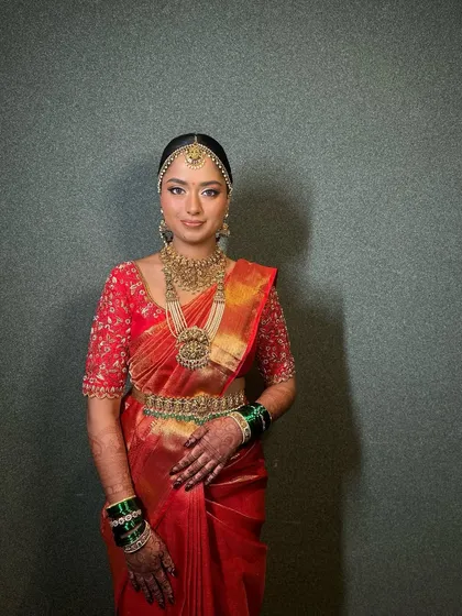 A portrait showing the complete look, from the matha patti to the layered necklaces, all balanced by a radiant makeup look.