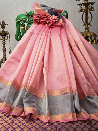 A soft pink silk saree with a contrasting grey and gold border. This elegant and understated piece is perfect for formal occasions and daytime events.