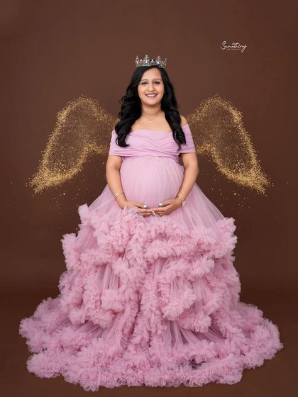 A touch of magic with this angel-themed portrait. The mother-to-be wears a pink ruffled gown and a tiara, with sparkling angel wings added for a dreamy, ethereal effect.