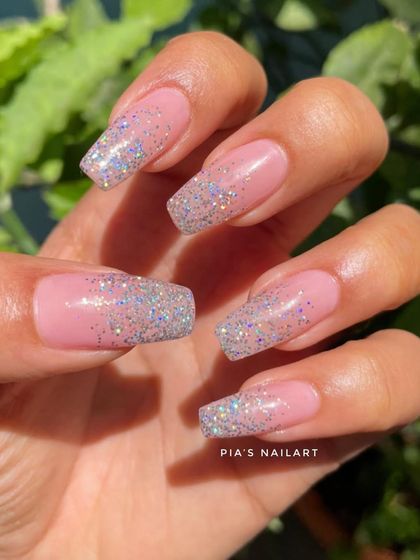 A client photo of her beautiful glitter ombre nail extensions, sparkling in the sun.