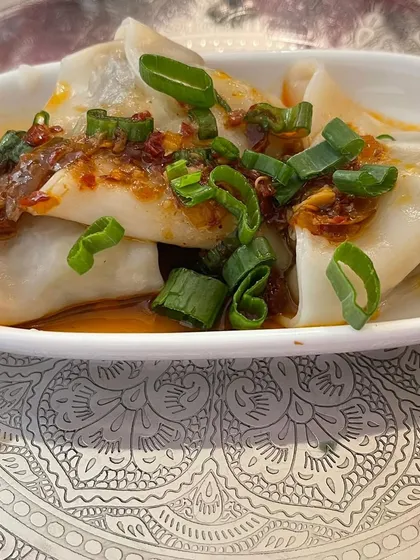 Our handmade chicken dim sum, glistening with chili oil and topped with fresh spring onions. We make these from scratch, ensuring the filling is juicy and the wrapper is perfectly delicate.