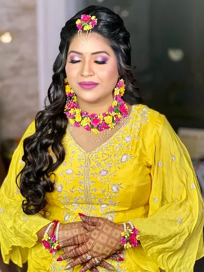 A serene, eyes-closed portrait that highlights the soft glam makeup and the freshness of the floral jewellery.