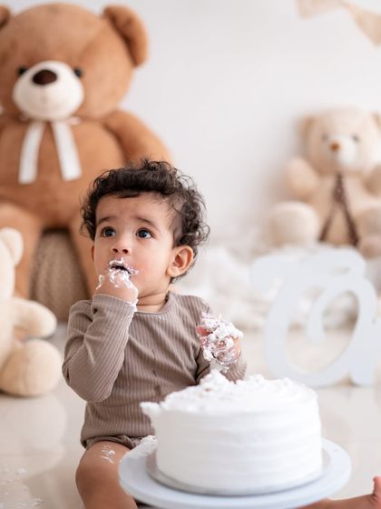 A teddy bear-themed cake smash. This little one is enjoying his first taste of cake, surrounded by furry friends.