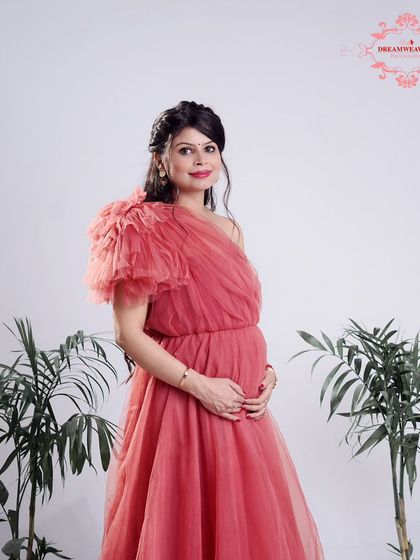 A full-length portrait of a glowing mother-to-be in a beautiful pink gown. Our studio sessions include access to a variety of maternity gowns to suit your style.