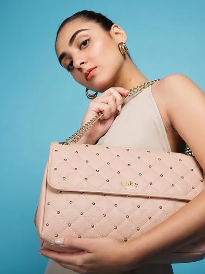 A clean, vibrant studio shot for luxury accessory brand Eské Global. The bright blue background makes the pastel pink quilted bag pop, creating a fresh and modern product-focused image.