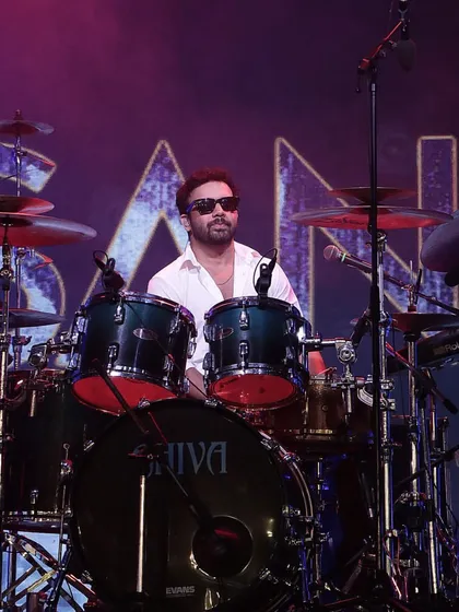 The drummer of Sanam Band, set against a large screen with the band's logo, showcasing our professional approach to stage and production design.
