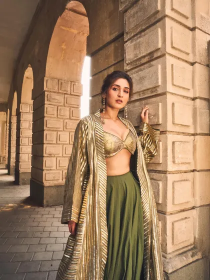 This look is all about making a statement. I paired a shimmering gold bralette and a modern olive lehenga with a structured, striped jacket to create a powerful fusion silhouette that’s perfect for a festive evening or a wedding reception.