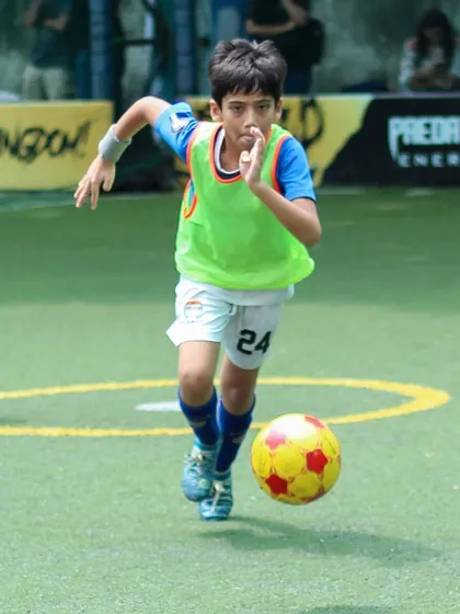 A young player dribbling with speed and control during an Intra-Cup match, showcasing his confidence on the ball.