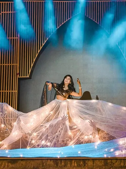 A bride's performance using a long, flowing fabric prop with embedded fairy lights. This creates a magical and ethereal effect on a dimly lit stage.