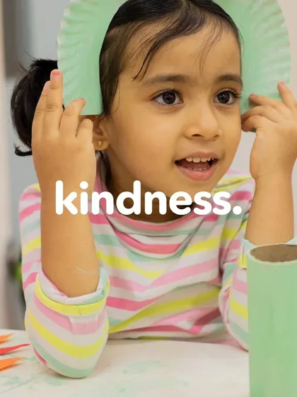 A young girl smiles as she works on her craft project. We believe that kindness and creativity go hand in hand, filling the world with sunshine.