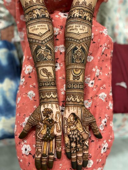 A beautiful bridal mehandi featuring portraits of the couple. The arms are adorned with Sanskrit shlokas, elephant motifs, and other auspicious symbols.