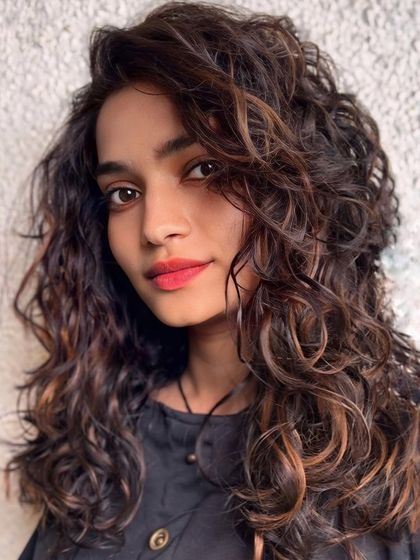 A golden glow on brunette curls. We use highlighting techniques to add a sun-kissed effect that makes every curl stand out.