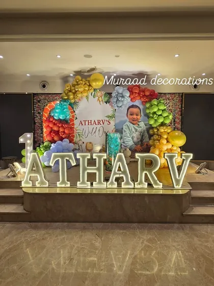 For Atharv's 'Wild One' party, we used large, illuminated marquee letters for his name to create a stunning stage. The setup was completed with a colorful balloon arch and a personalized backdrop featuring his photo.