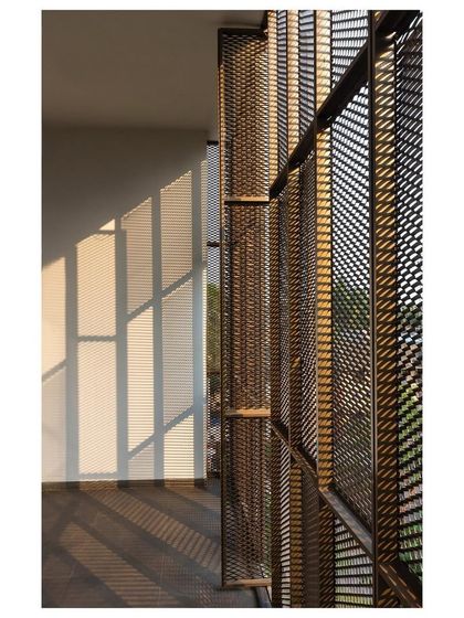 The afternoon sun casts a patterned shadow through the aluminum mesh screen onto the interior wall of the "Hoverspace" verandah, creating a dynamic and ever-changing light effect.