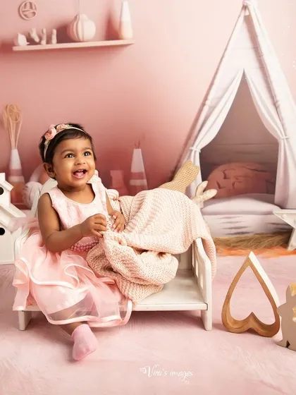 A smile that lights up the room. This toddler portrait features a little girl in a pink boho-themed setup, complete with a mini tent and bunny decorations.