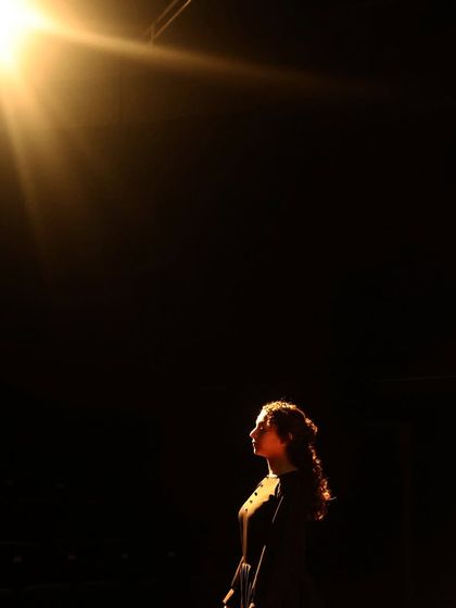 A single spotlight captures a moment of solitary reflection in "The House of Bernarda Alba," highlighting the individual desires that threaten to break the family apart.