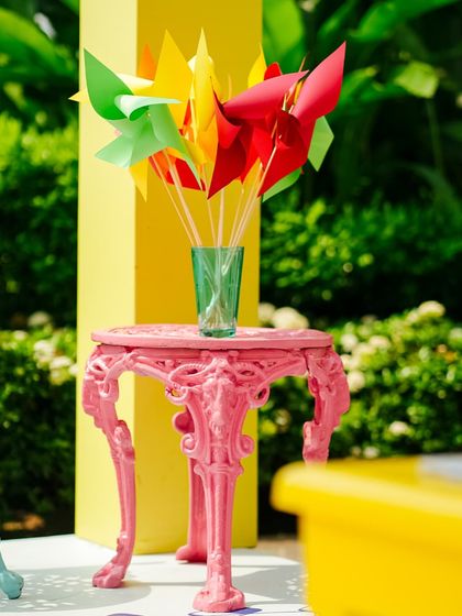 A small, ornate pink table holds a vase of colorful pinwheels, another example of the playful and quirky details that made this Haldi unique.