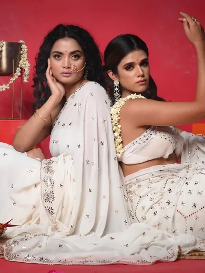 Another powerful shot from the same series, with the models back-to-back. The addition of mogra flowers in their hair adds a traditional and fragrant touch to the modern styling.