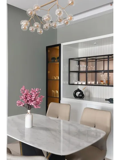 A closer look at a sophisticated dining setup. The combination of a white marble table, a modern bubble chandelier, and a sleek, built-in bar unit with internal lighting creates an atmosphere of refined luxury.