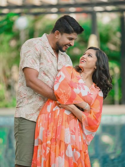 A relaxed and stylish poolside shoot. The lush green surroundings and calm water provide a beautiful, resort-like setting for casual and romantic couple photos.