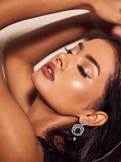 An artistic, expressive close-up. This shot highlights the flawless, glowing skin and the sharp, winged eyeliner, a classic combination for a powerful and glamorous look.