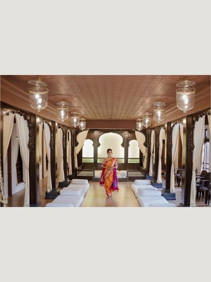 A wide shot of the bride walking through a beautifully decorated hall, her vibrant saree a stunning focal point.