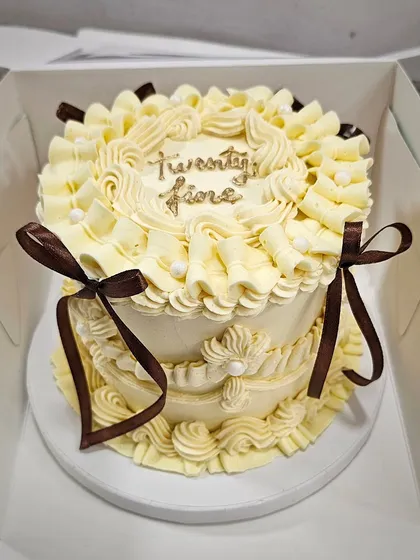 An elegant off-white vintage cake with delicate piping and chocolate-brown ribbon details for a sophisticated look.