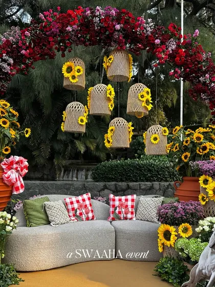 A cozy seating area at the baby shower, featuring a plush sofa, gingham-print cushions, and whimsical decor like hanging birdcages filled with sunflowers.