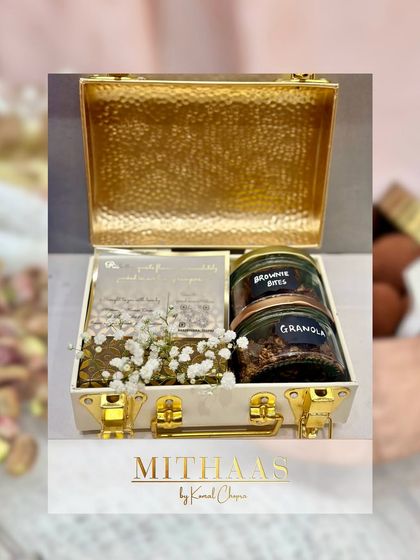 For a touch of modern luxury, I offer these hammered gold-finish metal briefcases. This one is packed with brownie bites and granola, adorned with baby's breath for a delicate contrast.