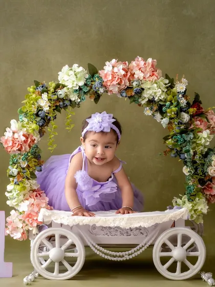 Dressed in a beautiful lavender gown, this little princess is ready for her first birthday portrait. The floral carriage prop adds a touch of fairytale magic to the scene.