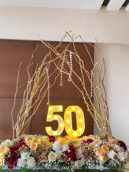 The 50th birthday centerpiece with the marquee numbers lit, casting a warm glow on the beautiful arrangement of roses, carnations, and chrysanthemums.