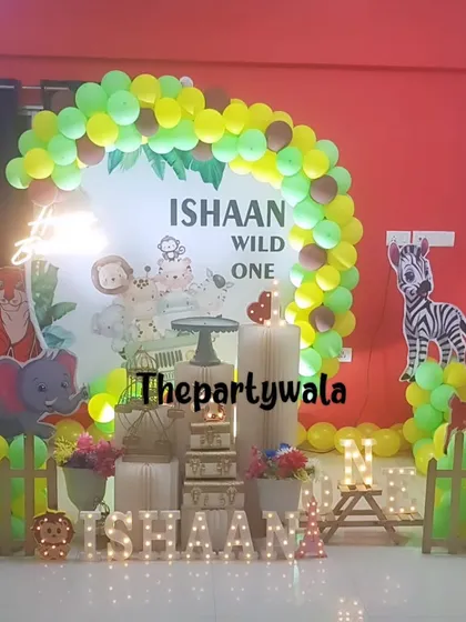 A "Wild One" jungle theme party, perfect for a first birthday. This setup includes a custom backdrop, cute animal cutouts, and a green and yellow balloon arch.