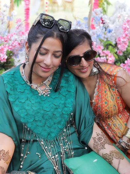 A quiet moment between the bride and her friend or sister during a colorful boho-themed mehendi party.