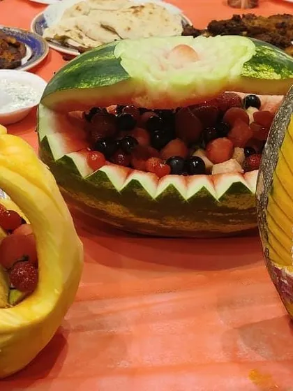 Food is art. I love adding these special touches, like intricate fruit carvings, to the table. This watermelon and pumpkin carving adds a beautiful, handcrafted element to the buffet spread.