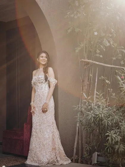 Carnival ready in a beautiful lace gown. The makeup is soft and ethereal, with a focus on glowing skin and a romantic braided hairstyle, perfect for a sunlit outdoor event.