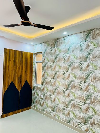 A bedroom featuring a bold tropical print wallpaper alongside a custom wardrobe with a dual-tone wood and blue finish.