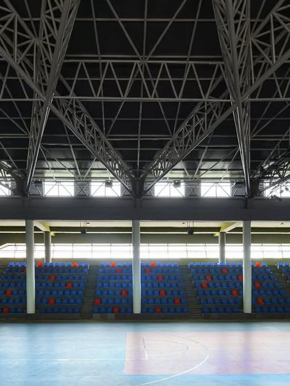The seating tiers of the sports arena, with the expansive roof structure visible above. Clerestory windows bring in natural light without causing glare on the playing courts.