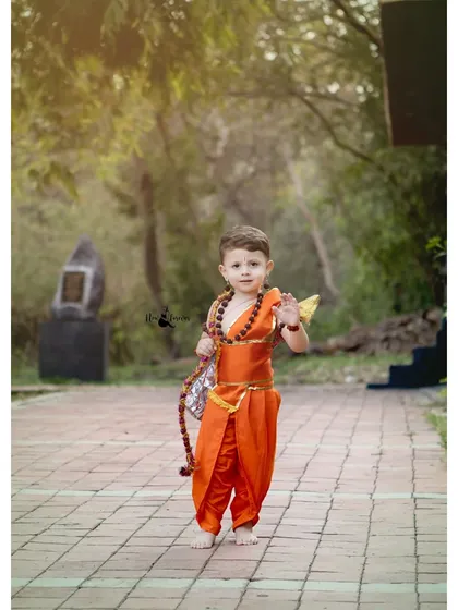 A confident little Lord Ram walks along a path, holding his bow. The natural outdoor setting and beautiful light make this a powerful and inspiring portrait.