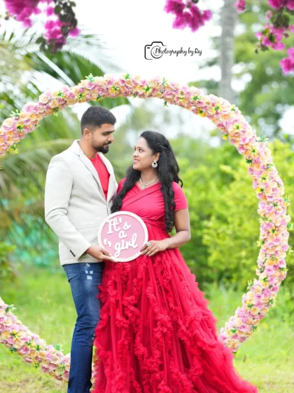 A sweet gender reveal moment. This couple uses a sign to announce "It's a girl!" while posing within a circular floral frame.