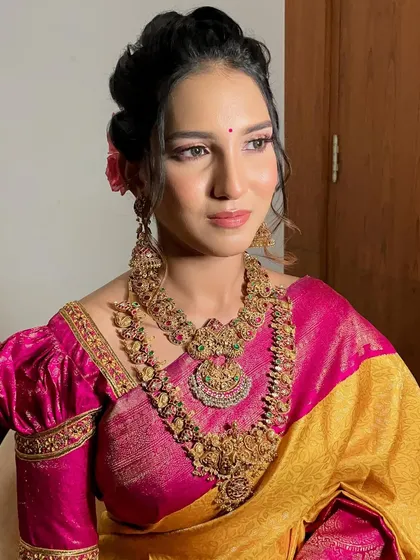 A picture-perfect moment capturing the essence of this soft glam look. The pink eyeshadow and matching lip harmonize beautifully with her yellow and pink silk saree and antique jewelry.