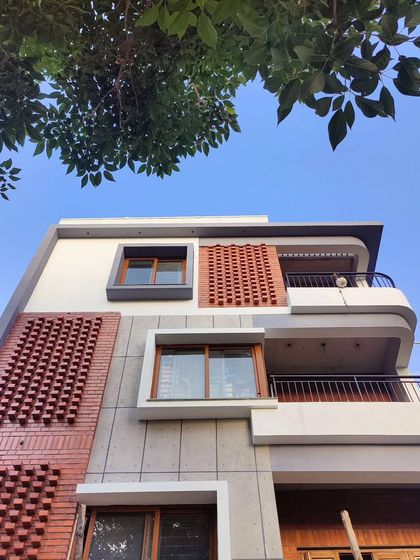 The Akshaynagar residence nearing completion. This view shows the projecting brick facade that contrasts with the grey concrete texture, scaling down the four-floor structure.