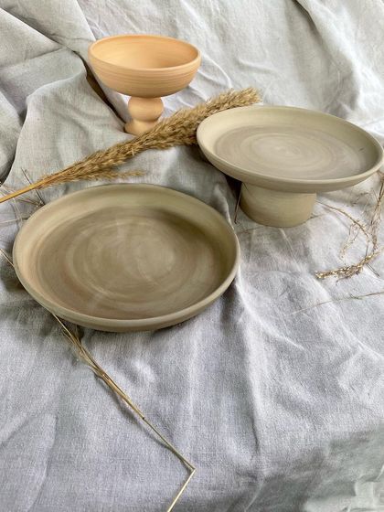 Prototypes from a professional course student, featuring elegant, footed plates and bowls with a subtle marbled clay effect.