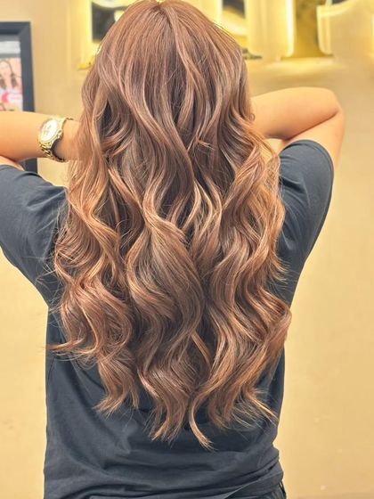 A back view of a client's long, wavy hair with a fresh color. The light catches the different tones, creating a beautiful, multi-dimensional effect.