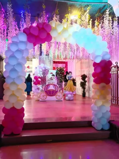 A grand entrance to a princess party, featuring a colorful balloon arch and a ceiling draped with hanging floral decorations.